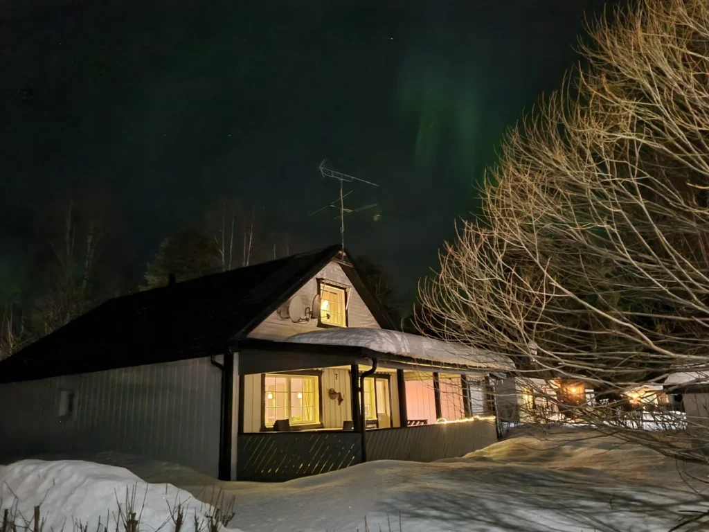 A wooden house in the snow under the northern lights