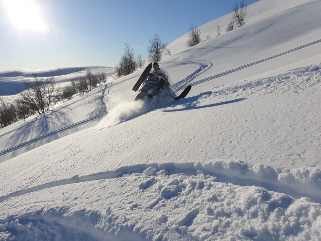 Snowmobile gift card: a snowmobile in deep powder snow on a sunny day in Swedish Lapland